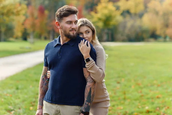 一位年轻貌美的孕妇在秋天的公园里依偎在一起 拥抱了她有男子气概的丈夫 — 图库照片