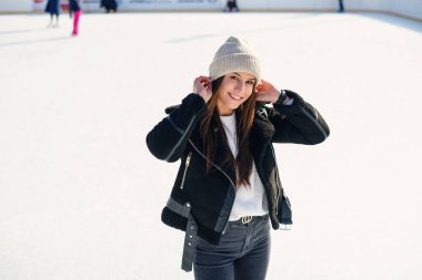 Mükemmel gülüşlü güzel bir kadının portresi açık havada buz pateni pistinde eğleniyor. Neşeli genç bayan Noel buz pateni pistinde kayıyor. Kış tatili dışarıda