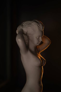 Kadınlar alçı heykel, modern sanat. Siyah zemin üzerinde sarı ışık bulunan sanat heykeli