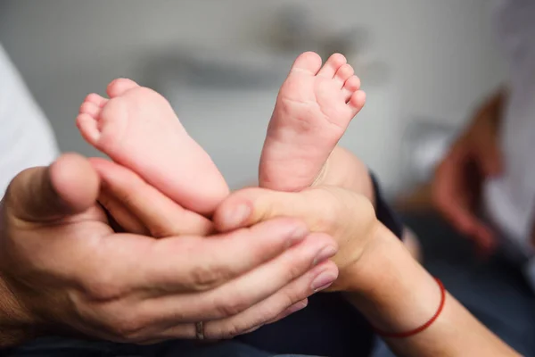 一个新生婴儿的脚在父母手里 快乐的家庭观念 妈妈和爸爸抱着孩子的腿 — 图库照片