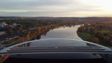 Günbatımında Prag 'daki Vltava nehrinin üzerinden geçen araçlarla modern köprünün üzerinde yavaş bir uçuş..