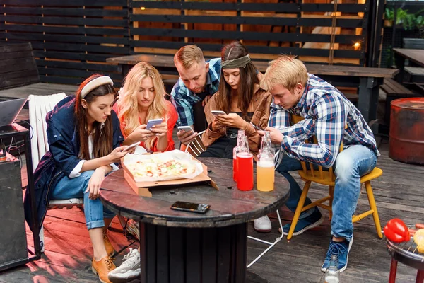 Group of friends looking at their smartphones at a boring party. Concepts of technology and modern lifestyle problems.