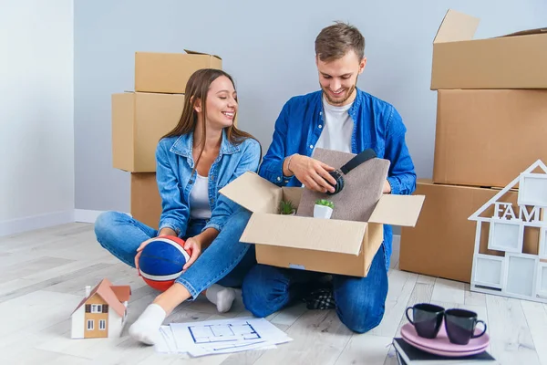 Young couple unpacking their things from boxes after moving into new house.
