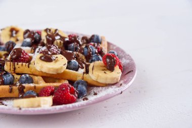 Yaban mersini, ahududu, muz ve şeker tozlu lezzetli Belçika tatlı waffleları sıvı çikolatayla doludur..