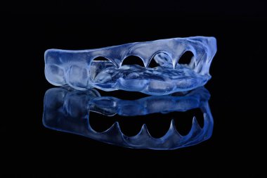 Siyah arkaplanda sakız düzeltmesi için 3D şeffaf diş kalıbı çıktı. Estetik dişçilik kavramı.
