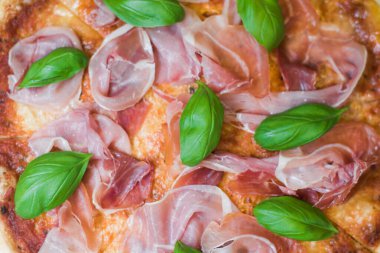 Prosciutto, peynir ve fesleğenli lezzetli bir dilim pizza. Amerikan tarzında yakın plan bir pizza..