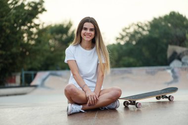 Modern kaykay parkında beyaz tişörtlü ve spor ayakkabılı çekici bir kız. 80-90 'ların ruhu, Miami tarzı..