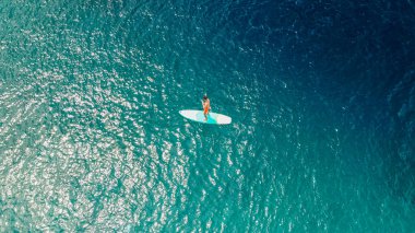 Sap sörfü, hava manzarası. Sörf tahtasının üstünde duran kürekli bir adam. Aktif eğlence, denizdeki spor. Ayakta sörf ve güzel deniz günbatımı.