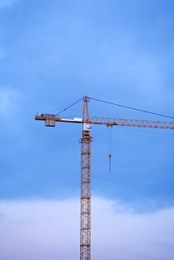 Gün batımında gökyüzünün arka planında birkaç vinç var. Yeni konut kompleksinin inşaatı.