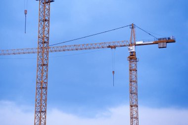 Gün batımında gökyüzünün arka planında birkaç vinç var. Yeni konut kompleksinin inşaatı.