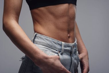 Karın kasları zayıflama ve zayıflama gösteren mükemmel vücutlu bir kadının yakın çekimi. Mükemmel vücutlu bir kızın karnına bir damla su..