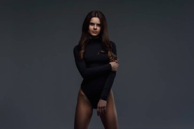 Koyu gri arka planda poz veren mükemmel vücutlu, ince, esmer bir kadın. Sağlıklı yaşam tarzı kavramı.