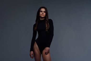 Koyu gri arka planda poz veren mükemmel vücutlu, ince, esmer bir kadın. Sağlıklı yaşam tarzı kavramı.