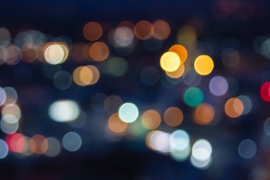 Soyut şehir ışıkları arka planı bulanıklaştırıyor. Yumuşak odaklı yatay uzun pankart. Bokeh, gece partisi şehri için koyu dokuya odaklanmış renkli ışıltılarını dağıtıyor. Bulanık kalıp şablonu.