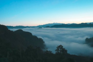 Doğal sis ve dağların arka planı bulanıklaşıyor, sisli dalgalar ılık renkler ve parlak güneş ışığı. Noel arkaplanı gökyüzü güneşli turuncu ışık desenleri, bulutlarda soyut aydınlatma akşamı bulanık.