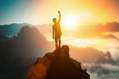 Silhouette of positive man celebrating on mountain top, with arms raised up, silhouette of man standing on the hill, Business, success,victory,leadership,achievement concept. Freedom travel adventure. clipart