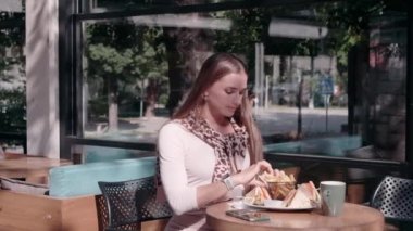 Kafede bir kız akıllı telefondan hamburgerle selfie çekiyor.