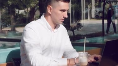 İşadamı kafede bilgisayar başında çalışıyor ve kahve içiyor.