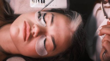 Kozmetik uzmanı, tıbbi ayna kullanarak çalışmanın kalitesini kontrol ediyor.