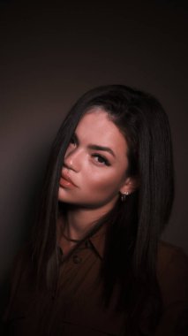 Kızın saçı yüzünün sağ tarafını kaplıyor. Kız bakıyor.