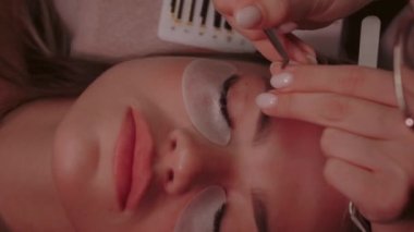 Kozmetik uzmanı kirpiklerini cımbızla salıyor ve yenilerini yapıştırıyor.