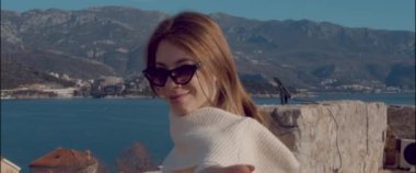 The girl calls to her and points her finger at the mountains