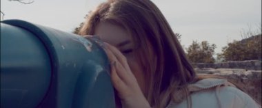 The girl on the observation deck looks through a spyglass