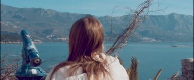 The girl approaches the spyglass on the observation deck