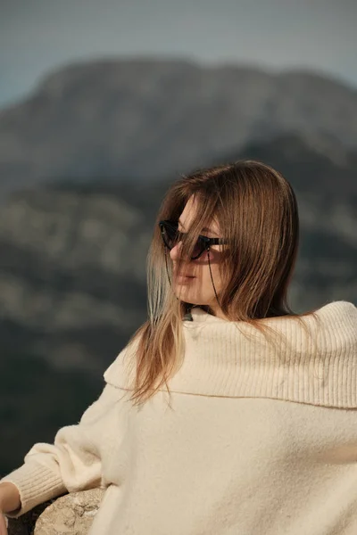 A girl with long hair stands in front of the camera in half a turn