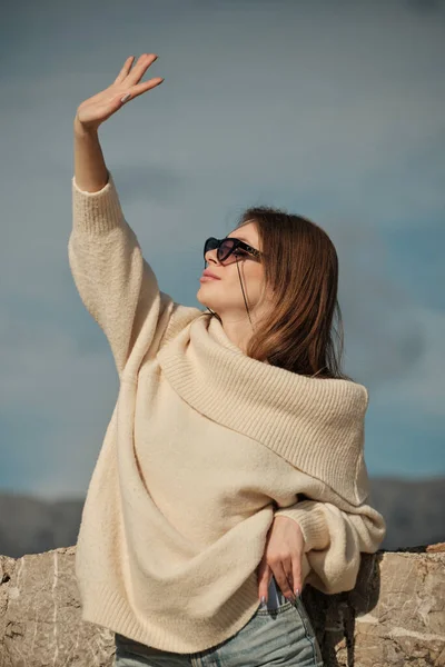 The girl looks at the sun through her fingers