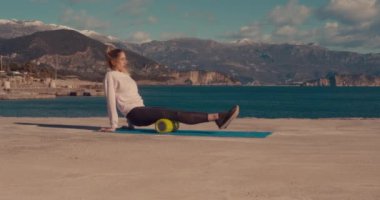 A girl is stretching her rear thigh muscles on a multi-purpose roller