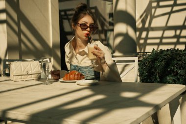 Açık bir kafede pipetle kahve içen bir kız.