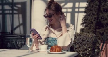 Yazlık kafede cep telefonuyla sohbet eden yetişkin bir kız.