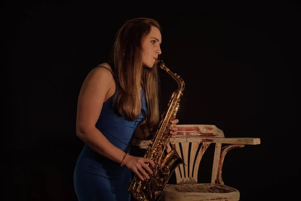 Beautiful white American woman plays saxophone solo on dark back