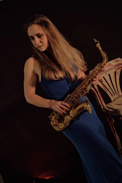 A beautiful white American woman holds a saxophone and prepares