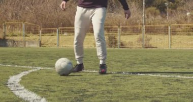 Erkek bir amatör futbolcu bacaklarının arasına eski bir futbol topu atıyor..
