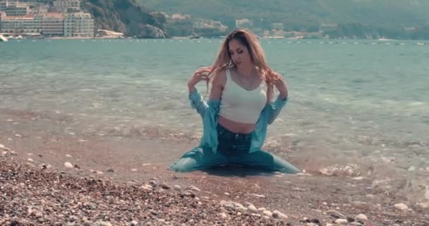 Islak Kot Elbiseli Genç Bir Kadın Sahilde Poz Veriyor Dağlar — Stok video