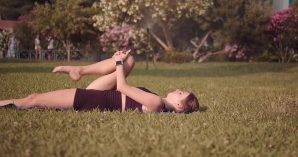 Çimlerin Üzerinde Uzanmış Bir Kız Bacaklarını Kalçalarını Sırt Kaslarını Çalıştırıyor — Stok video
