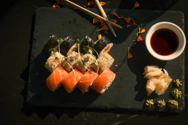 Bir tabak soslu suşi ve yemek çubuğu. Suşi renkli ve iştah açıcı bir yemek gibi görünecek şekilde düzenlenmiş. Sos küçük bir kaseye konur.