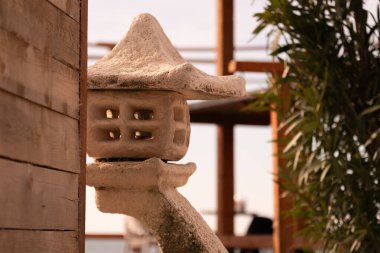 Çatısı olan küçük beyaz bir yapı ahşap bir duvarda duruyor. Yapı bir fener ve bir çıkıntının üzerine yerleştirilmiş. Sahne huzurlu ve huzurlu, fener rahatlatıcı bir atmosfer sağlıyor.