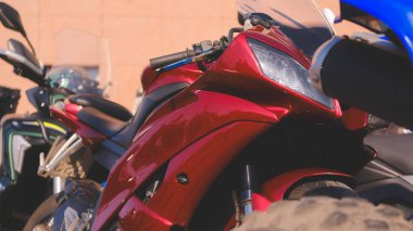 Kırmızı bir motosiklet mavi bir motosikletin yanına park edilmiştir. Görüntünün odak noktası kırmızı motosiklet.