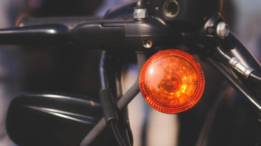 Motosikletin ön ışığı turuncudur. Motosikletin ön tarafına yerleştirilmiş. Işık açık, motosikletin etrafındaki alanı aydınlatıyor.
