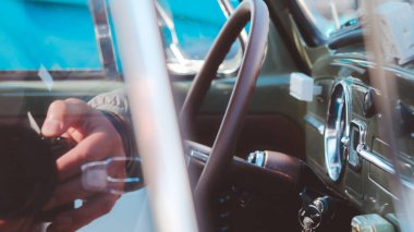 Deri direksiyonu olan yeşil bir araba. Araba bir otoparka park edilmiş.