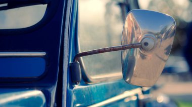 Yan tarafında ayna olan mavi bir araba. Ayna paslanmış ve üzerinde siyah bir leke var.