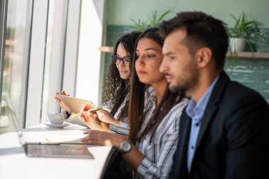 Yaratıcı iş adamları ofiste dizüstü bilgisayarı paylaşıyor, başlangıç sunumunu, tasarım projesini izliyor, fikirleri tartışıyor, beyin fırtınası yapıyor, monitörü işaret ediyor, konuşuyor. Ofis çalışanları bilgisayarda toplanıyor