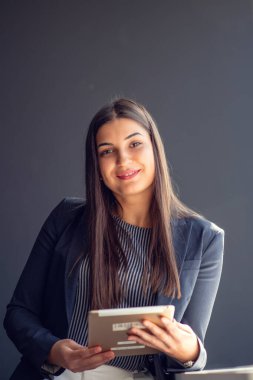 Genç çekici kadın Yöneticisi duran modern Office dijital tablet üzerinde çalışan.