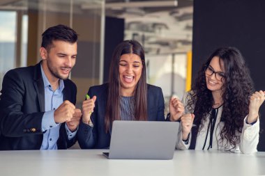 İş ekibi dizüstü bilgisayar kullanarak proje üzerinde işbirliği yapıyor. Güncel ofis ortamında sıradan iş arkadaşları birlikte çalışıyor. Takım çalışması konsepti
