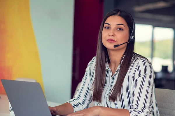 Young friendly operator woman agent with headsets working in a call centre