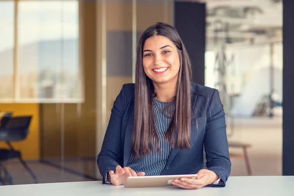 Stock image Young attractive female manager working on digital tablet while standing in modern office.