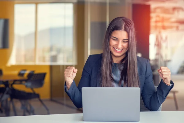 在办公室工作的年轻的黑发女人 手握手提电脑 做着积极的手势 微笑着竖起大拇指 快乐地工作着 快乐的表达和胜利的姿态 — 图库照片